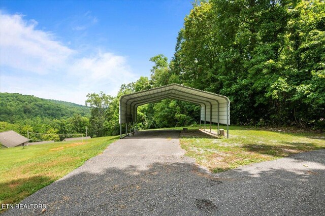 667 Pine Hollow Rd, Jacksboro, TN 37757 - surrounding community with asphalt driveway, a detached carport, a yard, and a forest view