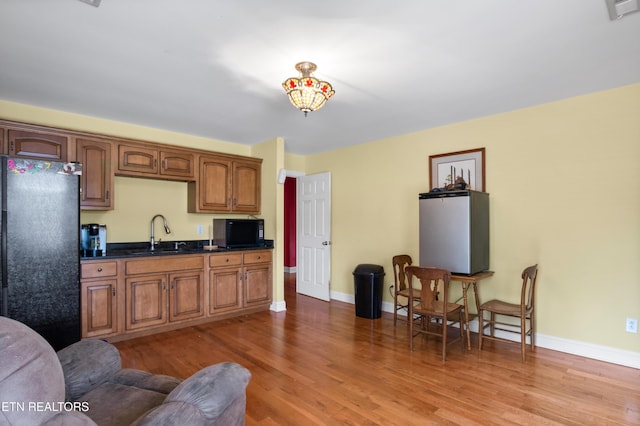 201 Locust Dr, Lafollette, TN 37766 - kitchen with black appliances, dark countertops, light wood-style floors, and brown cabinetry