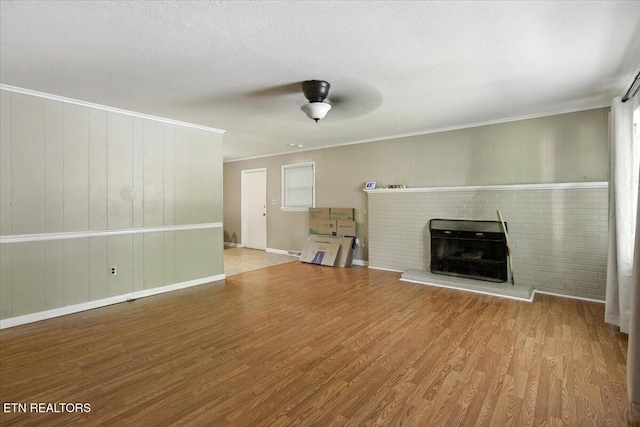 428 Wilderness Rd, Middlesboro, KY 40965 - unfurnished living room featuring wood finished floors, ceiling fan, a brick fireplace, and ornamental molding