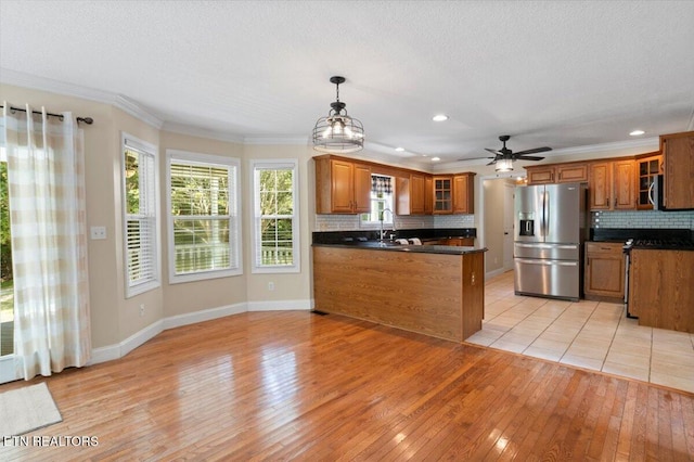 440 Indian Hills Rd, Oneida, TN 37841 - kitchen with stainless steel appliances, a peninsula, brown cabinets, light wood-style floors, and dark countertops