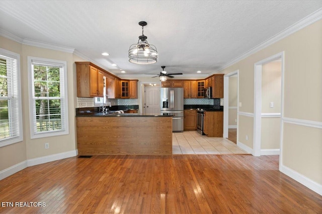 440 Indian Hills Rd, Oneida, TN 37841 - kitchen featuring stainless steel appliances, brown cabinets, dark countertops, a peninsula, and ornamental molding