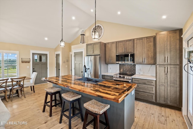 1721 Holly Bend Dr, Byrdstown, TN 38549 - kitchen with stainless steel appliances, wood counters, an island with sink, light wood-style floors, and high vaulted ceiling