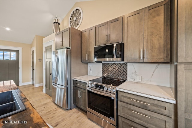 1721 Holly Bend Dr, Byrdstown, TN 38549 - kitchen featuring stainless steel appliances, lofted ceiling, decorative backsplash, light wood-style flooring, and light stone countertops
