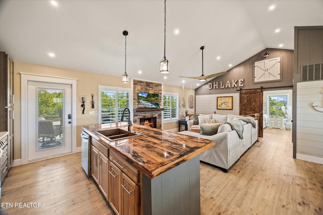 1721 Holly Bend Dr, Byrdstown, TN 38549 - kitchen with a stone fireplace, light wood finished floors, a kitchen island with sink, a barn door, and lofted ceiling