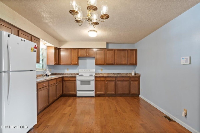 546 Park Rd, Caryville, TN 37714 - kitchen with white appliances, brown cabinetry, a textured ceiling, light wood finished floors, and a chandelier