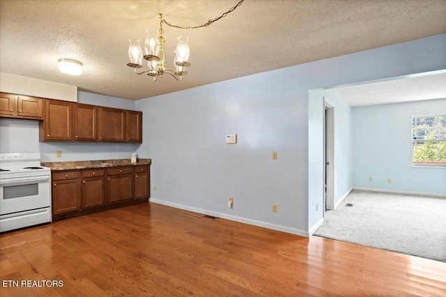 546 Park Rd, Caryville, TN 37714 - kitchen featuring white range with electric stovetop, a chandelier, a textured ceiling, wood finished floors, and brown cabinetry