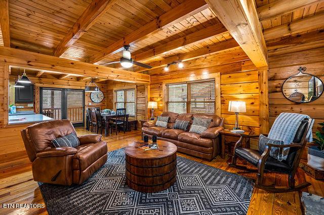 3322 Covered Bridge Way, Sevierville, TN 37862 - living area with wood walls, wood-type flooring, a wooden ceiling with exposed beams, and a ceiling fan