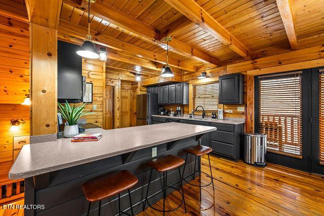 3322 Covered Bridge Way, Sevierville, TN 37862 - kitchen featuring hardwood / wood-style floors, a peninsula, wood walls, a wooden ceiling with exposed beams, and freestanding refrigerator