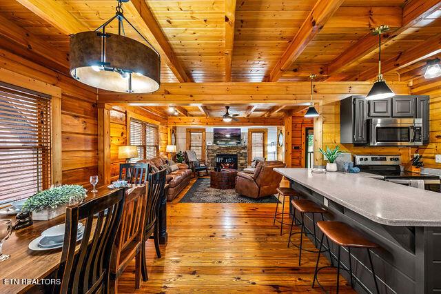 3322 Covered Bridge Way, Sevierville, TN 37862 - dining area featuring wooden walls, plenty of natural light, wood-type flooring, a stone fireplace, and ceiling fan
