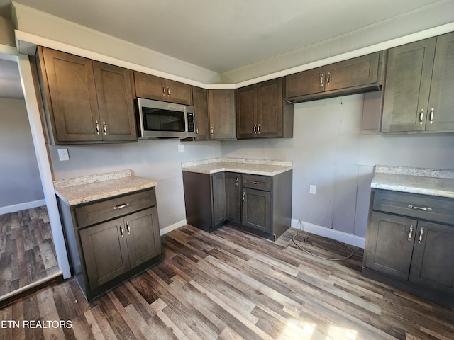 308 E Prospect St, Lafollette, TN 37766 - kitchen with stainless steel microwave, dark brown cabinetry, wood finished floors, and light countertops