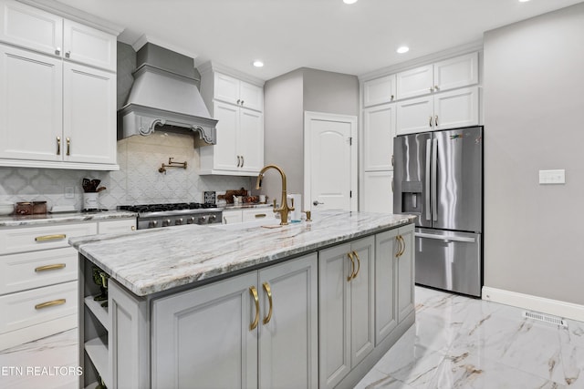 kitchen featuring appliances with stainless steel finishes, recessed lighting, light marble finish floors, backsplash, and a center island with sink