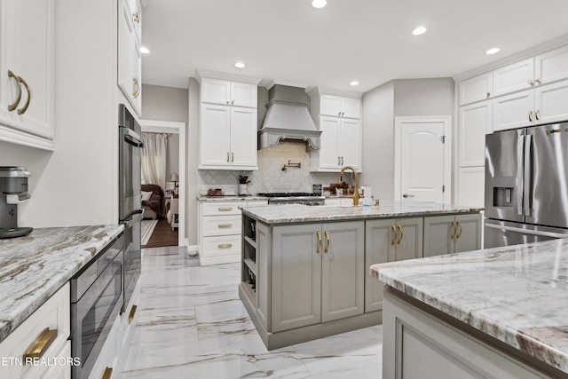 kitchen featuring stainless steel appliances, tasteful backsplash, recessed lighting, light stone counters, and an island with sink