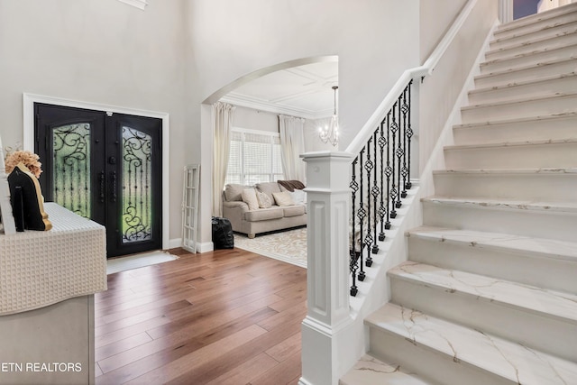 foyer entrance with arched walkways, hardwood / wood-style flooring, stairs, a high ceiling, and french doors