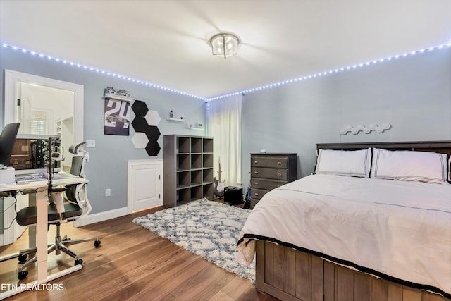 bedroom featuring wood finished floors and an office area