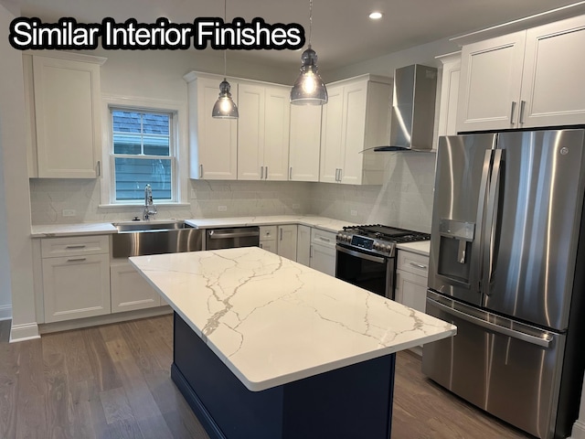 kitchen with appliances with stainless steel finishes, wall chimney exhaust hood, white cabinets, a center island, and hanging light fixtures