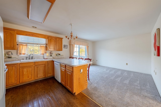 kitchen with a peninsula, white dishwasher, light countertops, dark carpet, and a sink