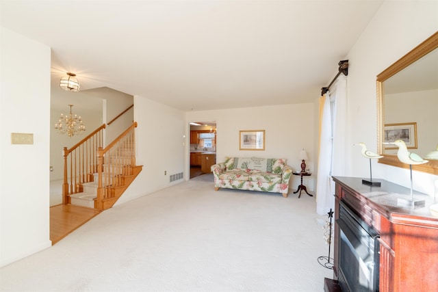 living room with carpet floors, a fireplace, visible vents, stairway, and an inviting chandelier