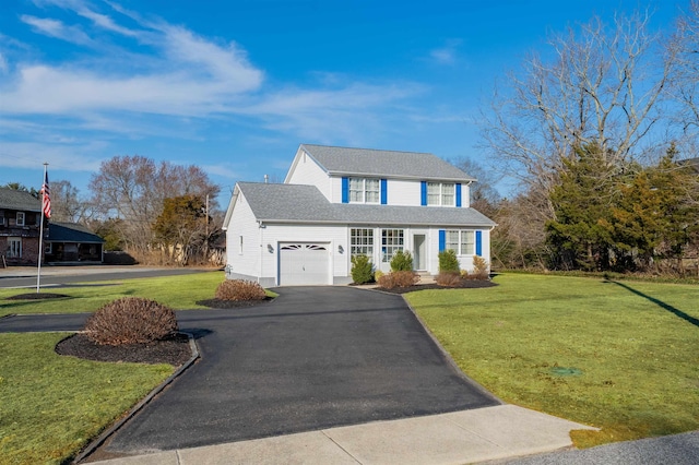 traditional-style house featuring a garage, a front lawn, and aphalt driveway