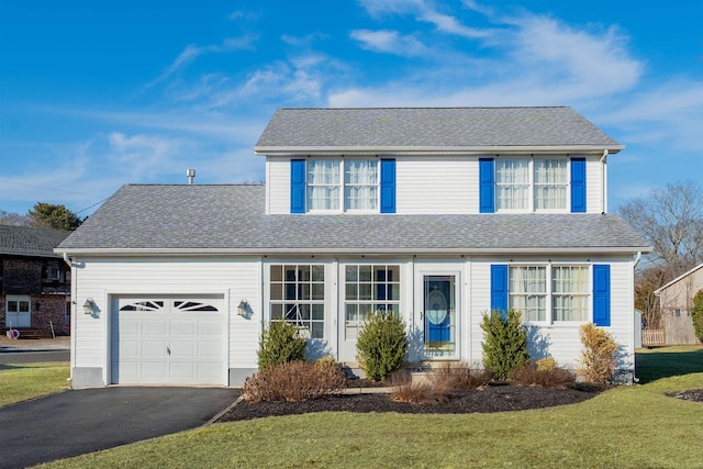 traditional home featuring a front lawn, roof with shingles, an attached garage, and aphalt driveway