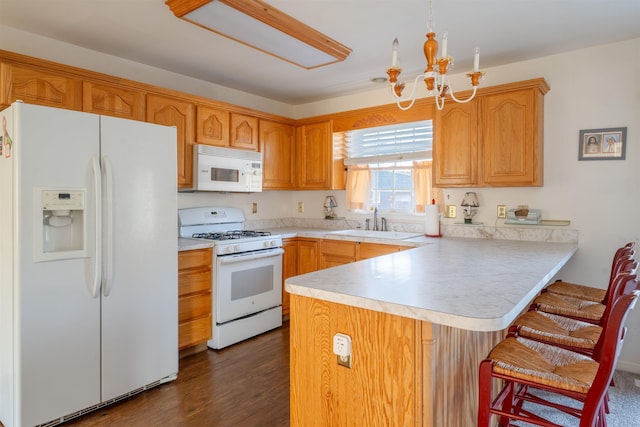 kitchen featuring white appliances, a breakfast bar, a peninsula, light countertops, and a sink