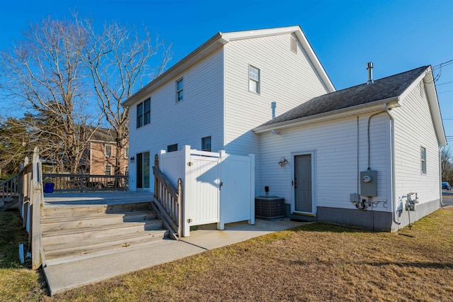 back of property with central air condition unit, a lawn, and a wooden deck