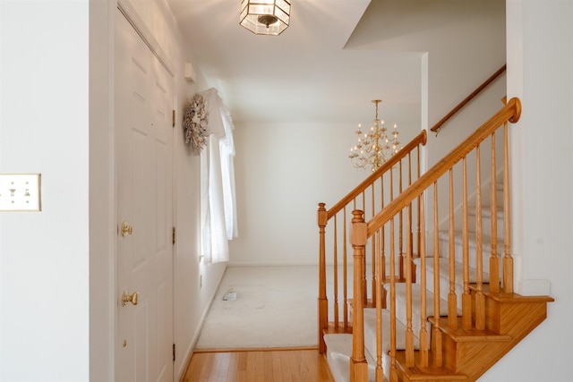 entrance foyer with stairs, a notable chandelier, baseboards, and wood finished floors