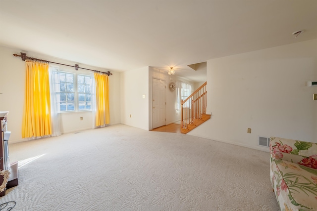 living area with carpet floors, visible vents, and stairs