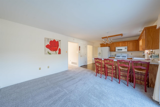 kitchen with white appliances, a breakfast bar area, a peninsula, light countertops, and a notable chandelier