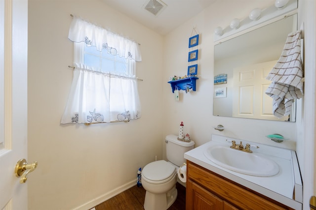 bathroom with visible vents, toilet, vanity, wood finished floors, and baseboards