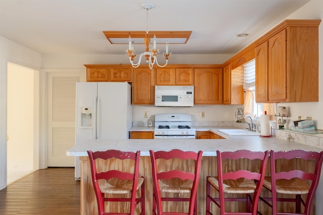 kitchen with a notable chandelier, light countertops, a sink, white appliances, and a peninsula