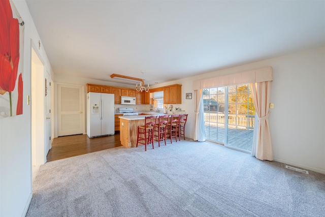 kitchen featuring white appliances, visible vents, a peninsula, light countertops, and carpet flooring