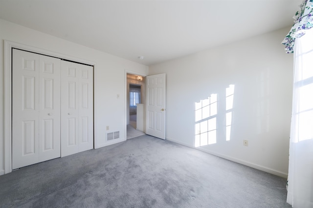 unfurnished bedroom with carpet floors, a closet, visible vents, and baseboards