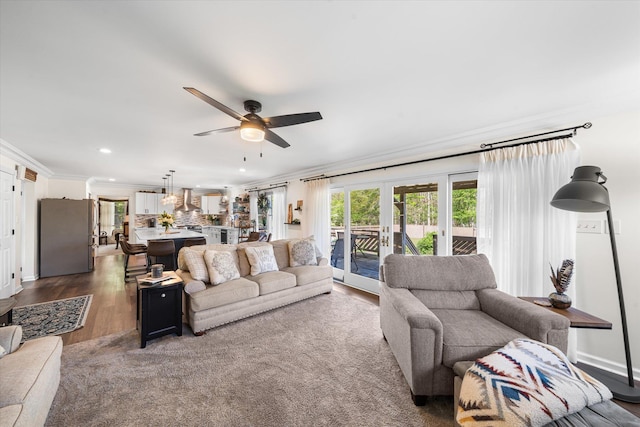 living room with dark wood-type flooring, ceiling fan, french doors, and crown molding