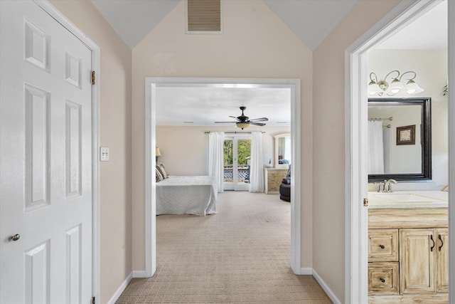 corridor featuring light carpet, vaulted ceiling, and sink