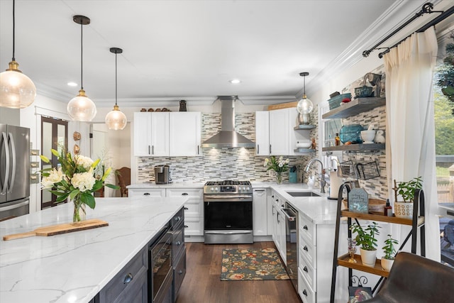 kitchen featuring hanging light fixtures, stainless steel appliances, wall chimney range hood, and sink