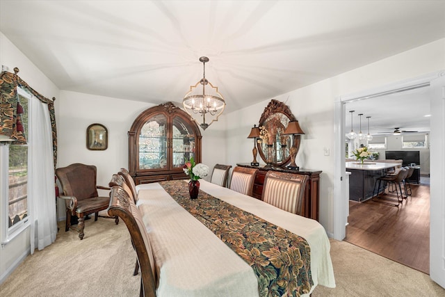 dining space featuring light carpet and ceiling fan with notable chandelier