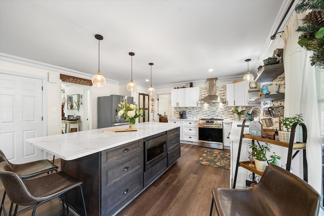 kitchen featuring wall chimney range hood, tasteful backsplash, decorative light fixtures, white cabinetry, and stainless steel appliances