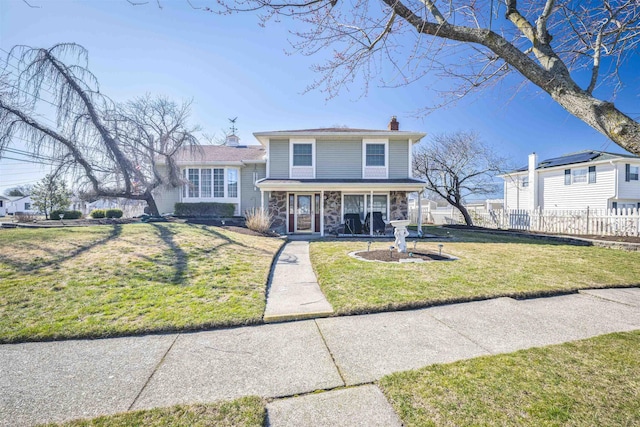 view of front of property with a front yard, fence, stone siding, and a chimney