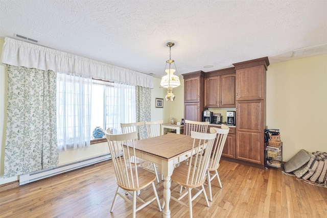 dining area with a textured ceiling, light wood-style floors, visible vents, and a baseboard radiator