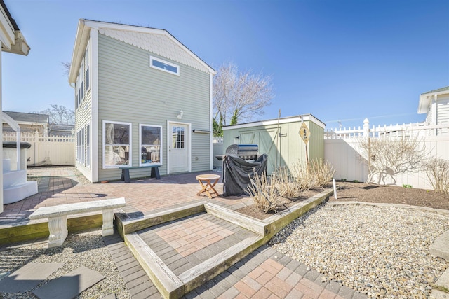 back of house featuring a patio area, a storage shed, an outbuilding, and a fenced backyard