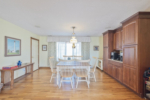 dining area featuring light wood-style flooring and a textured ceiling