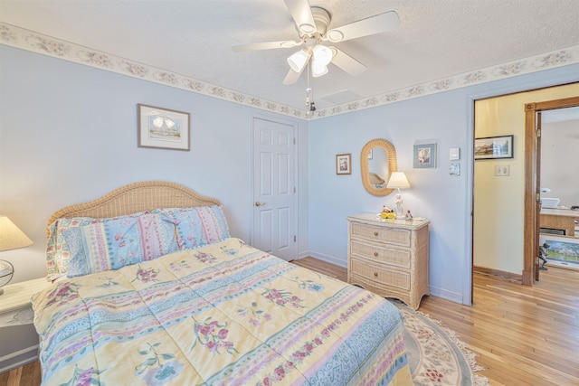 bedroom with wood finished floors, baseboards, and a textured ceiling