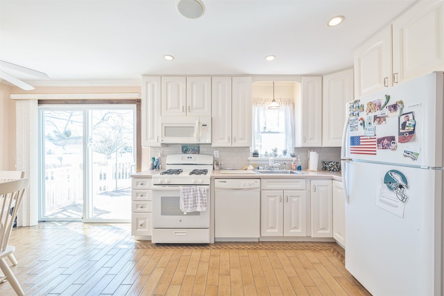 kitchen with white cabinetry, white appliances, backsplash, and a sink