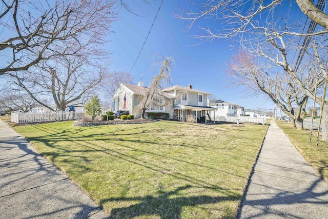 view of front of property with a chimney, a front yard, and fence