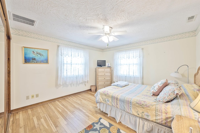 bedroom with light wood-style flooring, baseboards, visible vents, and ceiling fan