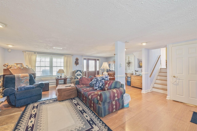 living area with stairway, a textured ceiling, and light wood finished floors