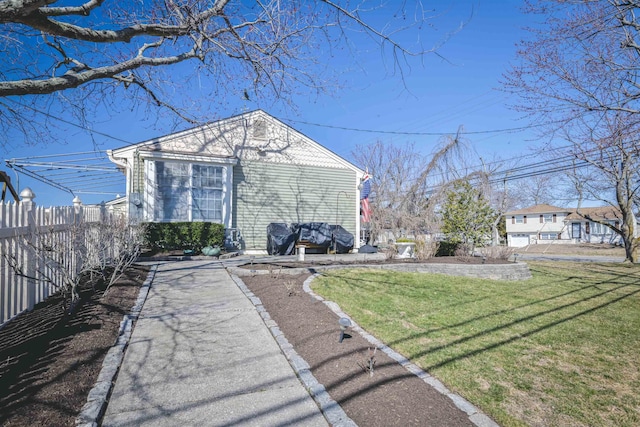 rear view of property featuring a lawn and fence