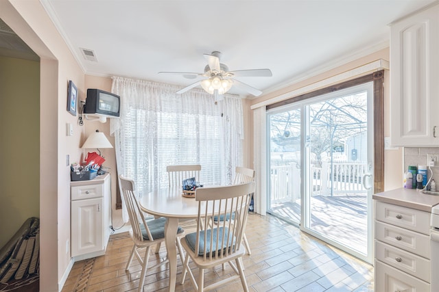 dining space with visible vents, a ceiling fan, and crown molding