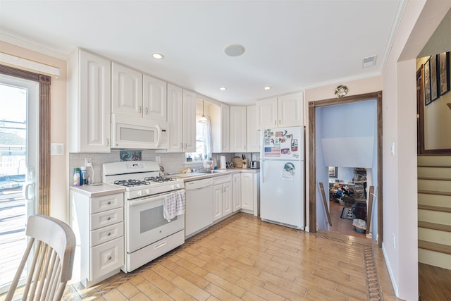 kitchen with visible vents, backsplash, white appliances, and white cabinets