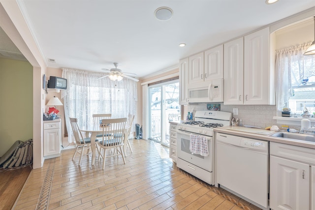 kitchen featuring ornamental molding, white appliances, white cabinets, light countertops, and decorative backsplash